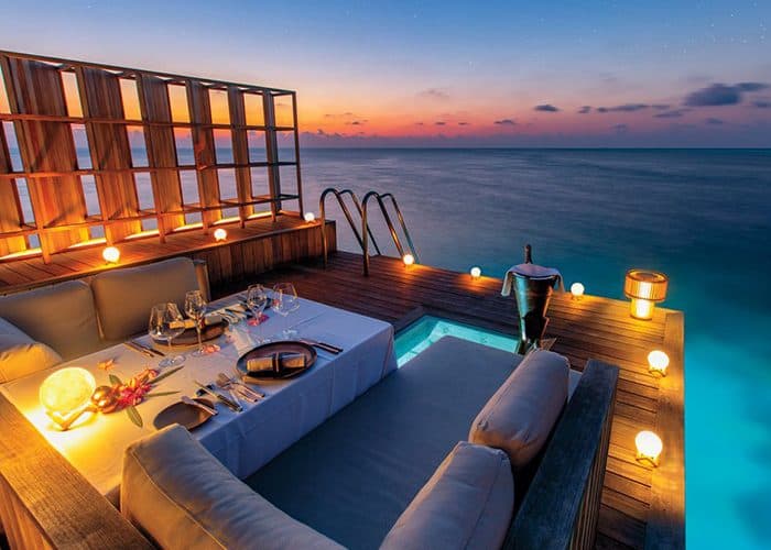 An overwater villa deck at dusk over the turquoise lagoon, Maldives
